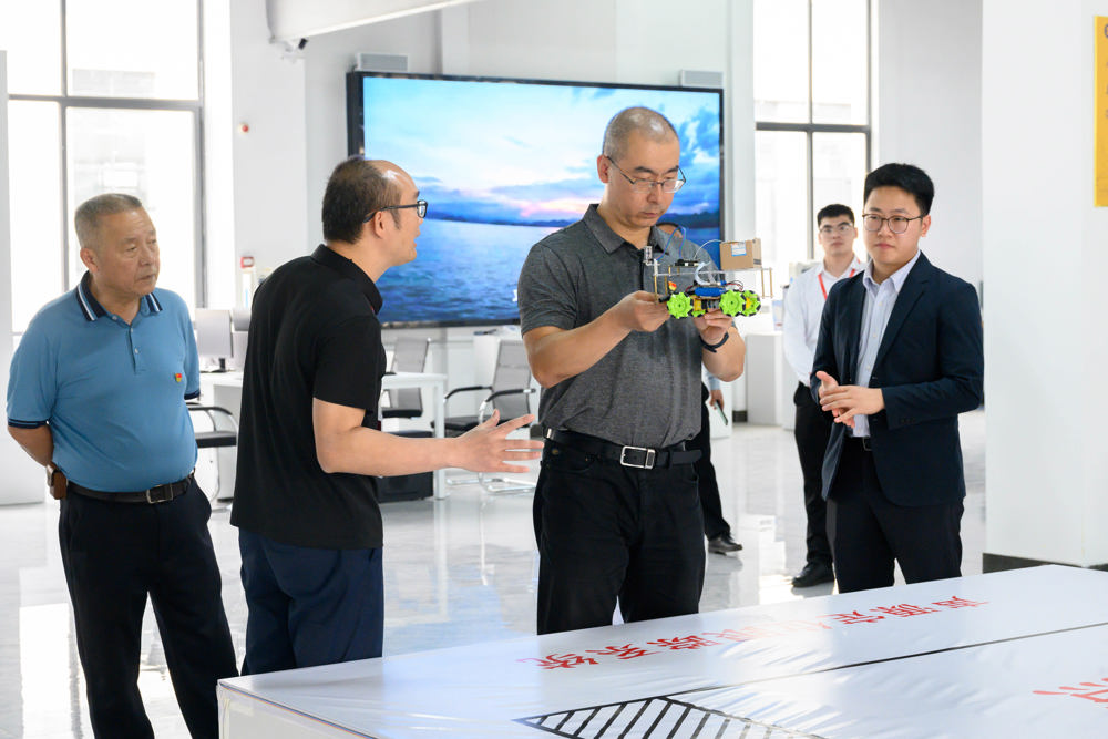 在智融科创实训基地，黄天旭老师向段然常委介绍由我校师生共同研发的智能声源定位小车